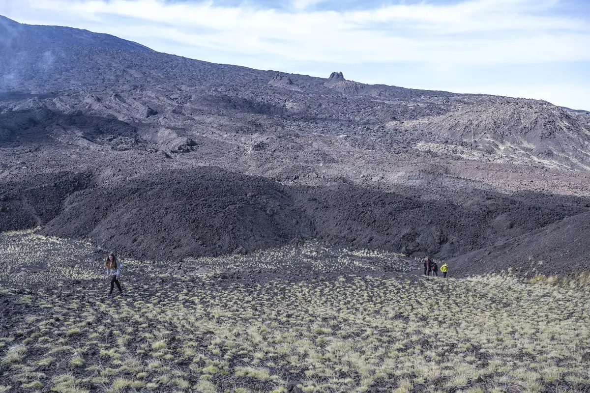Hikers crossing a lava field on Etna